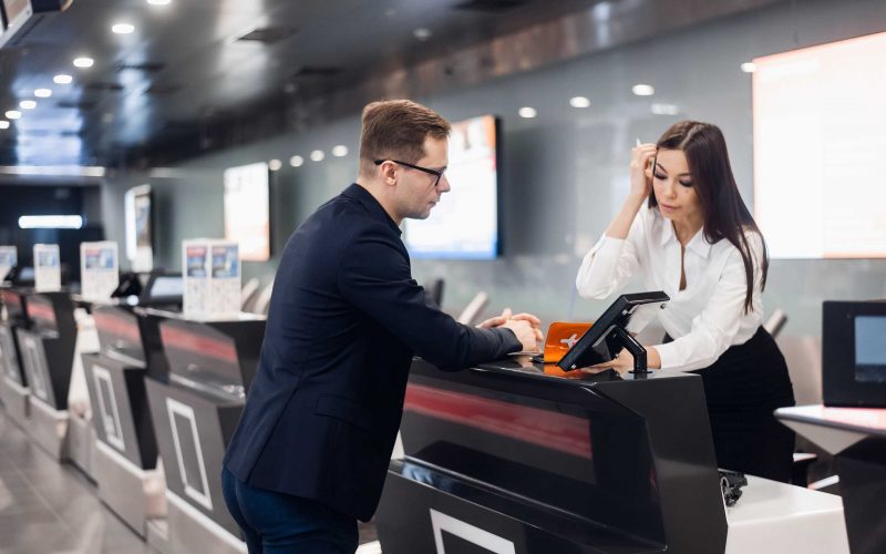 Персонал на стойке регистрации в аэропорту вручает билет бизнесмену