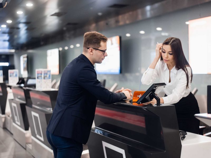 Персонал на стойке регистрации в аэропорту вручает билет бизнесмену